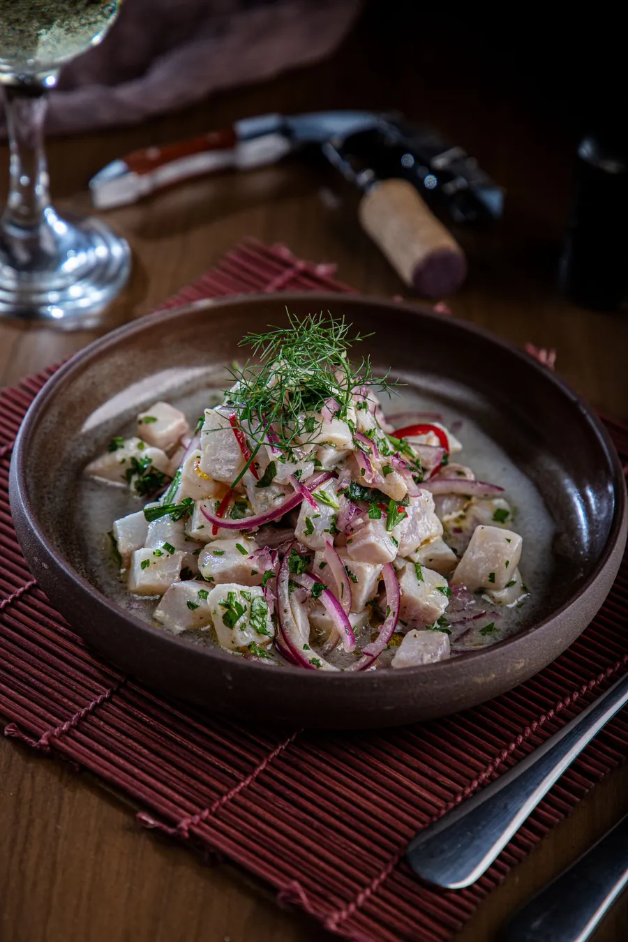 Ceviche de pescado con cebolla morada y cilantro en un bol oscuro